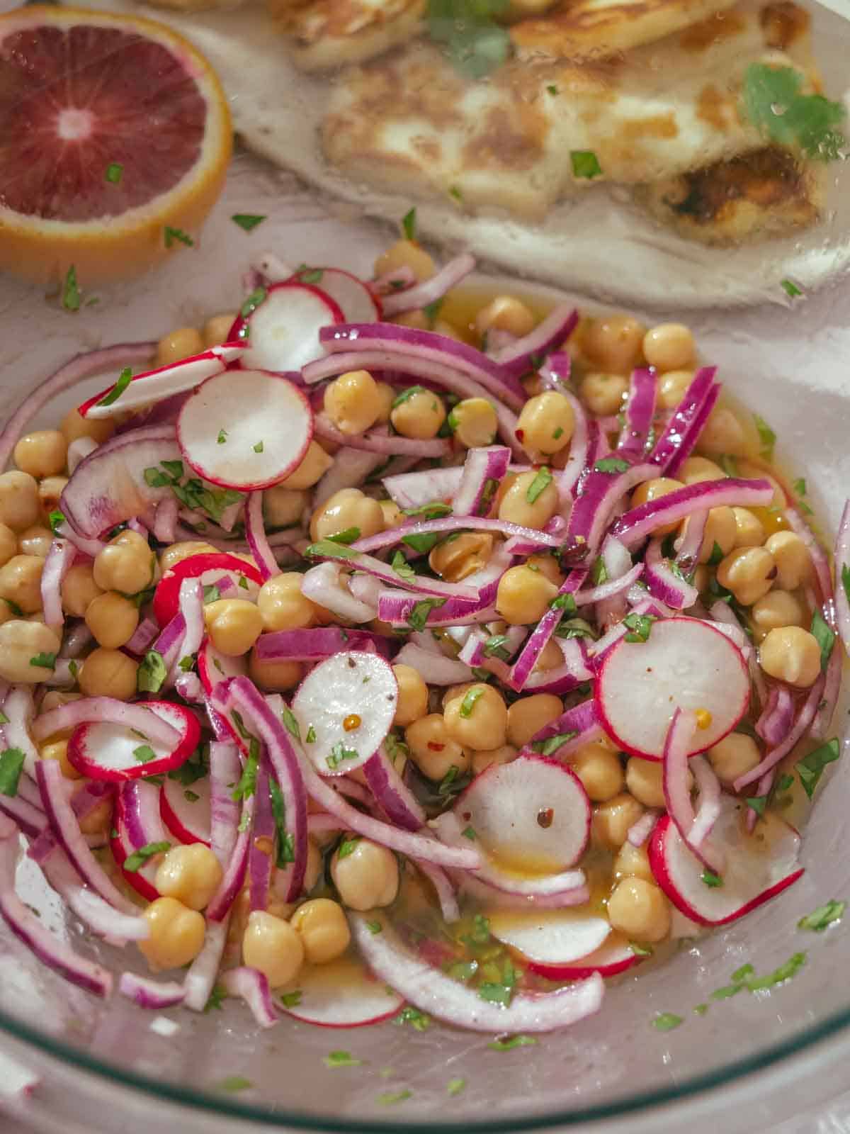 Sliced radishes, sliced red onion, and chickpeas are marinated in the vinaigrette.